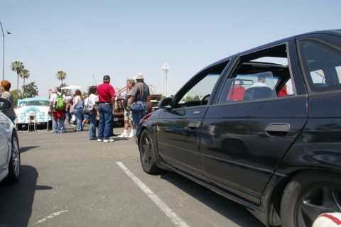 1992 Ford Taurus - Outdoor car show scene with multiple vehicles and attendees gathered.