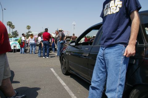 1992 Ford Taurus - A group of people gather around vehicles at an outdoor car show on a sunny day.