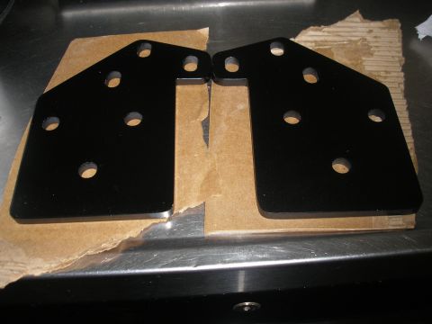 1995 Ford Bronco - Two black metal brackets with various holes are shown, resting on cardboard packaging.