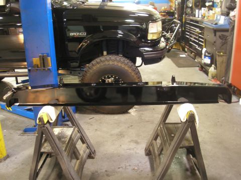 1995 Ford Bronco - A black Ford Bronco rear bumper is displayed on sawhorses in a workshop.