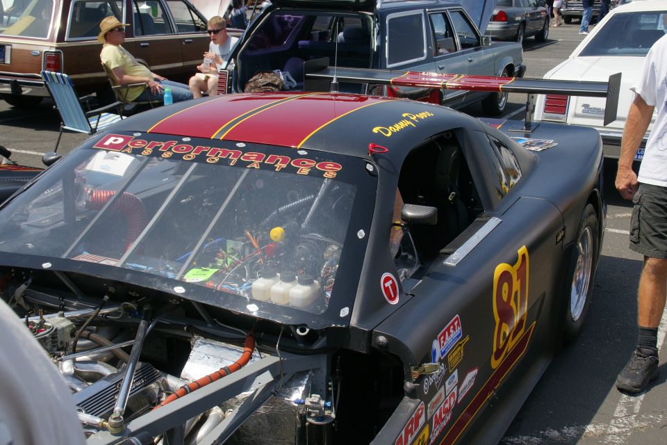 Black race car with red and yellow stripes, large spoiler, and 'Performance Parts' decal