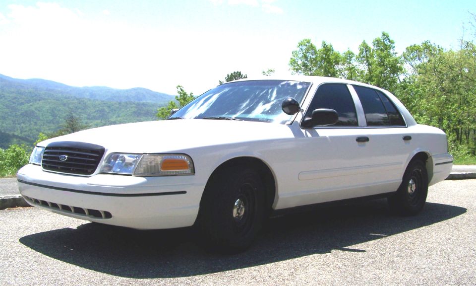 White 2000 Ford Crown Victoria parked outdoors with mountains in the background