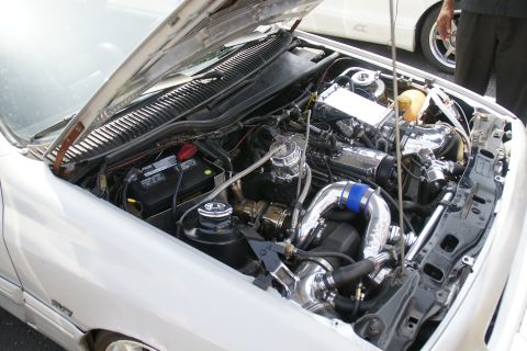 1992 Ford Taurus - The engine bay of a car is open, revealing a heavily modified engine with polished components and chrome components.