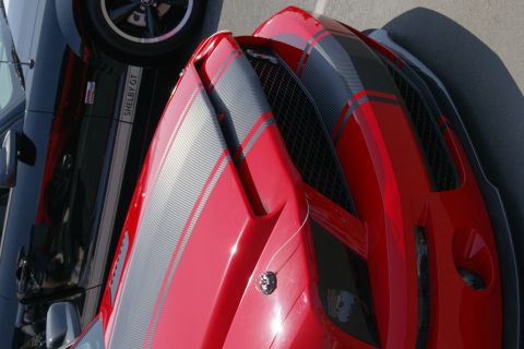 1992 Ford Taurus - A close-up view of the front of a red sports car parked next to a black Shelby GT.