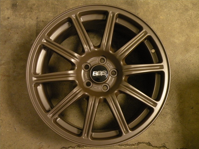 Bronze BBS multi-spoke alloy wheel without tire lying on concrete floor