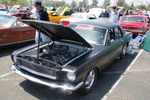 1992 Ford Taurus - A classic Ford Mustang is displayed with its hood up at an outdoor car show.