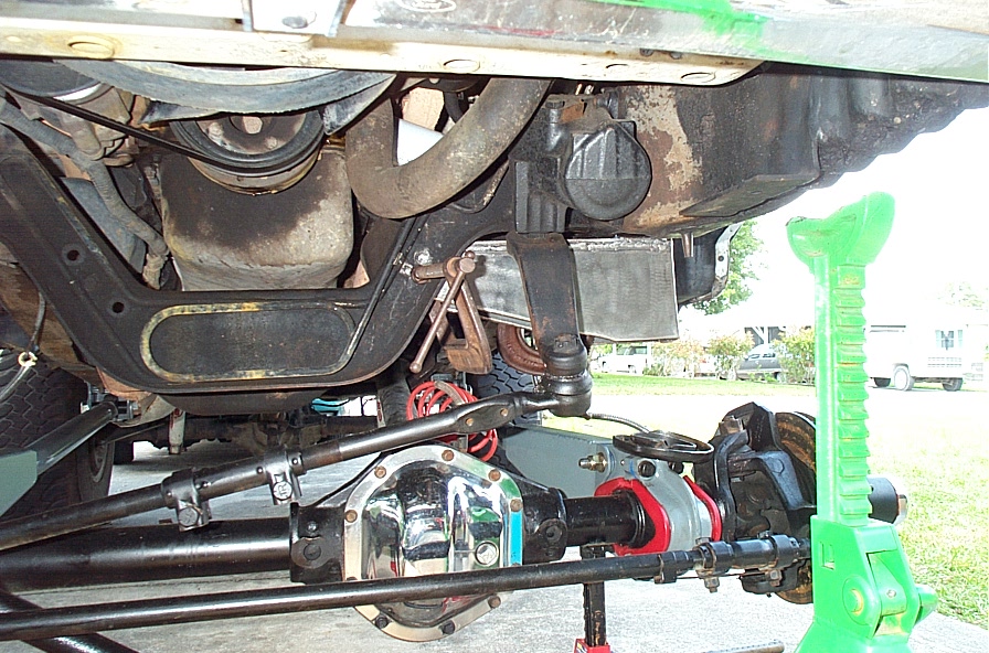 Underside of a 4x4 showing front axle, driveshaft, chrome diff cover and red bushings