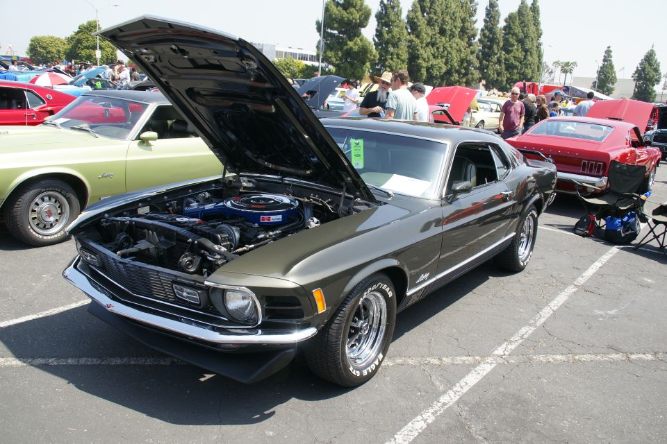1970 Ford Mustang Mach 1 with hood open, showing engine. Other cars visible in background