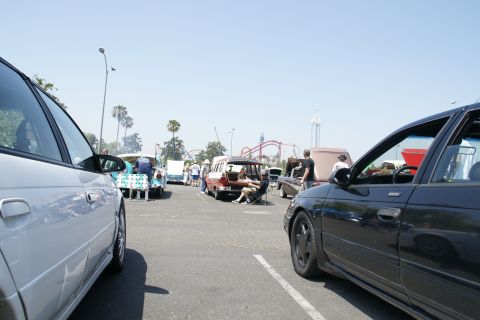 1992 Ford Taurus - A gathering of vehicles and people at an outdoor event, with a roller coaster visible in the distance.
