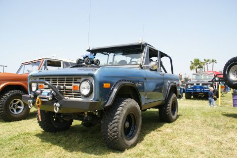 1992 Ford Taurus - A blue Ford Bronco is parked on grass with other vehicles in the background. A toy truck sits on its roof.