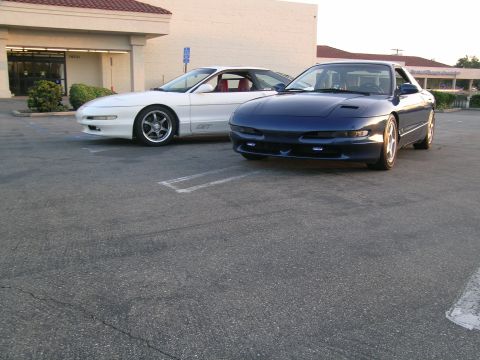 1993 Ford Probe - Two Ford Probes, a white GT and a blue model, are parked side-by-side in a parking lot.
