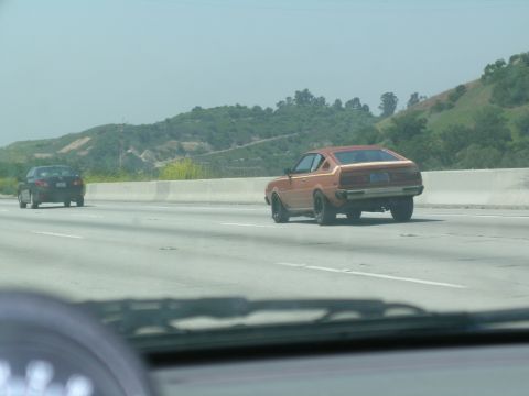 1993 Ford Probe - Two cars on a highway with hills in the background.