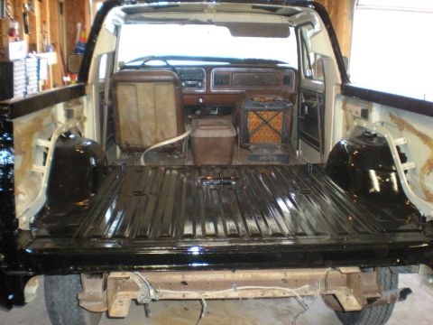 1978 Ford Bronco - The interior and bed of a Ford Bronco are shown, with the seats in worn condition and the bed appearing freshly painted black.