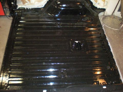 1978 Ford Bronco - The floor pan of a vehicle is shown with a black protective coating and visible structural ribs.