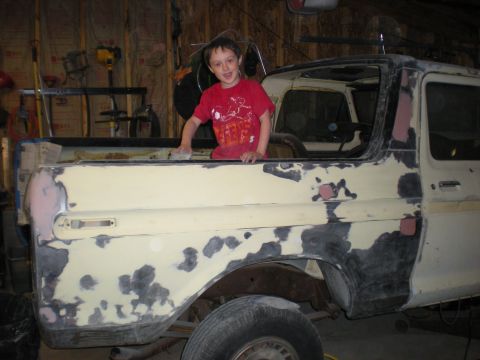 1978 Ford Bronco - A young boy poses inside a 1978 Ford Bronco during bodywork in a garage.