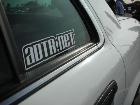 2004 Ford Crown Victoria - A white sedan is viewed from the side, showing a sticker on the rear passenger window.