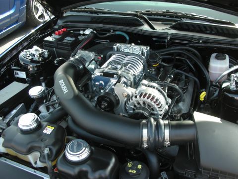 2004 Ford Crown Victoria - Close-up of a ROUSH supercharger system installed in a vehicle's engine bay.