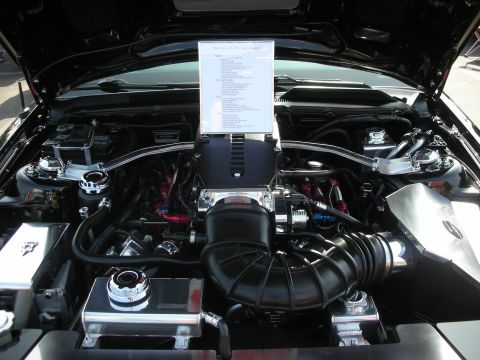 2004 Ford Crown Victoria - The engine bay of a car is shown with a supercharger and a detailed document placed on top.