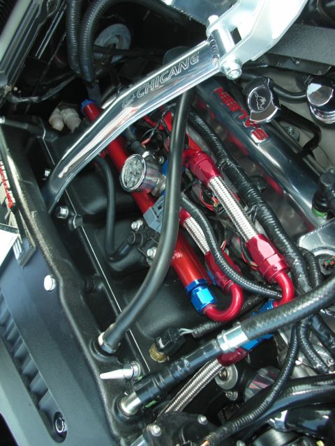 2004 Ford Crown Victoria - Engine bay modifications include a chrome strut bar and red braided fuel lines, with a visible gauge.