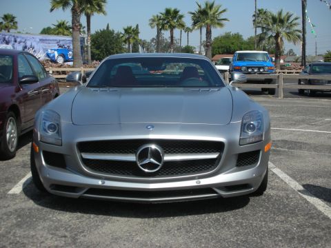2004 Ford Crown Victoria - A silver Mercedes-Benz SLS AMG is parked in a lot with other vehicles and palm trees in the background.