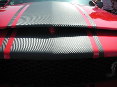 2004 Ford Crown Victoria - Close-up of a red car's hood carbon fiber stripes and red accents.