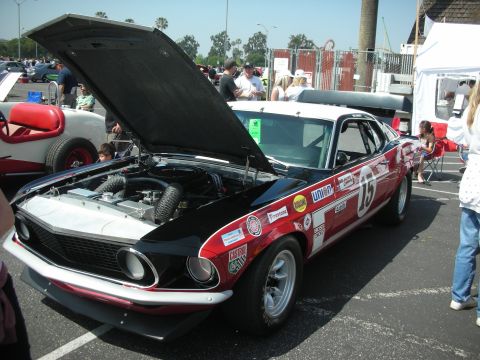 2004 Ford Crown Victoria - A vintage race car, likely a 1969 Ford Mustang Boss 302, is displayed with its hood up at an outdoor event.