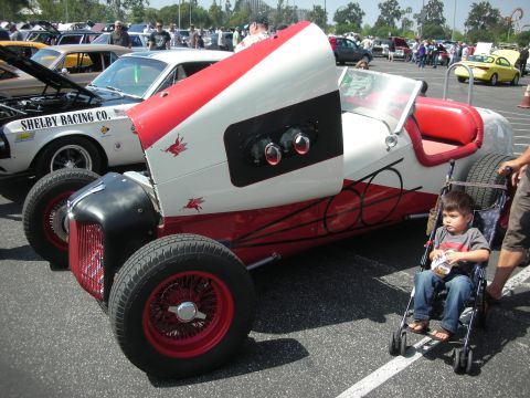 2004 Ford Crown Victoria - A custom race car with a distinctive red and white paint scheme is parked at an outdoor event.
