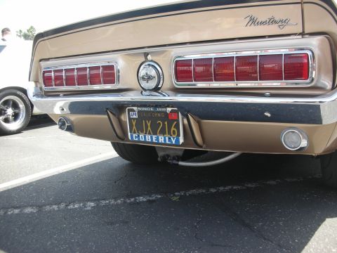 2004 Ford Crown Victoria - The rear of a gold 1969 Ford Mustang is visible, parked next to another vehicle.