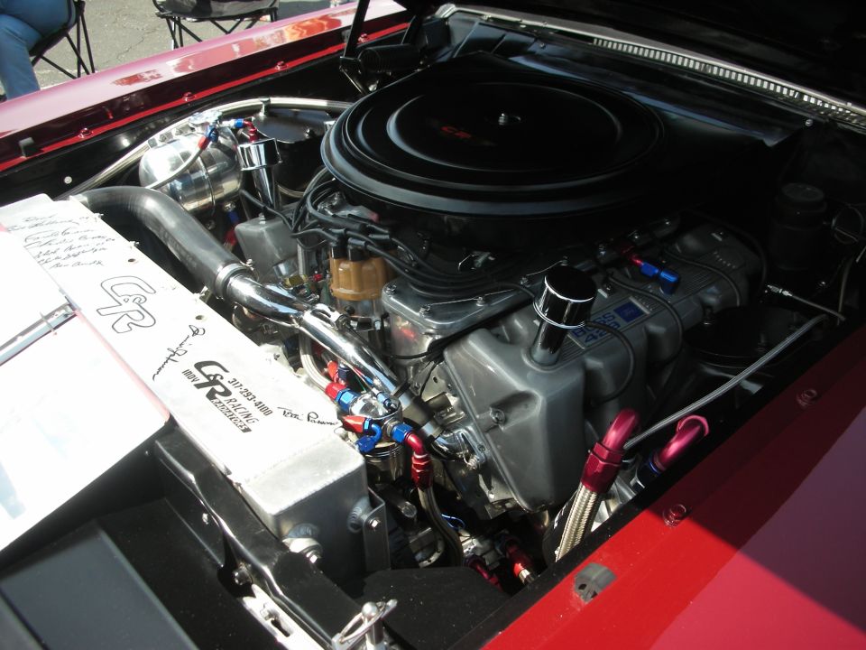 Engine bay with custom aluminum radiator, chrome components, and aftermarket engine parts. Radiator has GR Racing branding and phone number