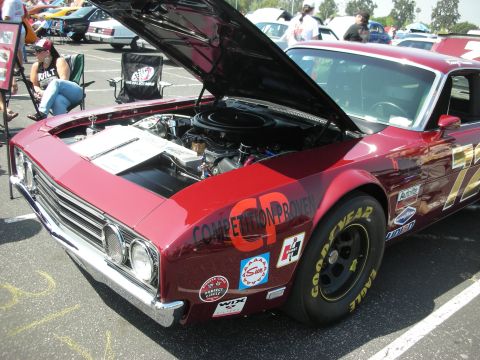 2004 Ford Crown Victoria - A red race car is displayed with its hood up, revealing the engine compartment and various racing decals on its body.