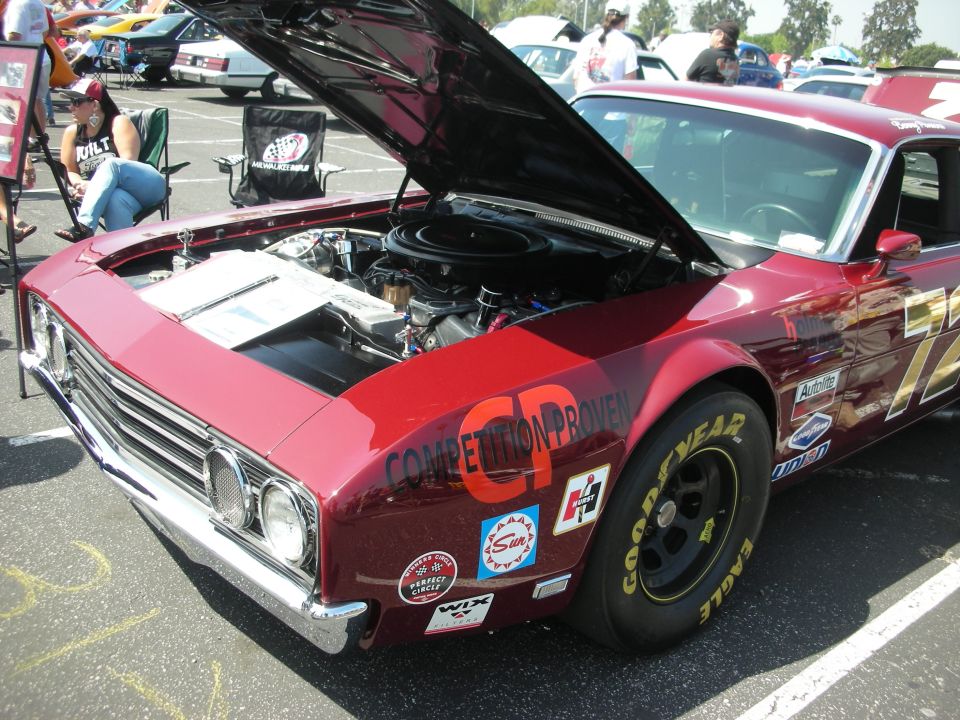 Red race car with hood open, showing engine. Has 'CP COMPETITION PROVEN' on fender and racing decals. Goodyear Eagle tires