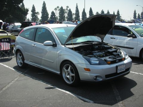 2004 Ford Crown Victoria - A silver 2004 Ford Focus hatchback is displayed with its hood open at a car show event.