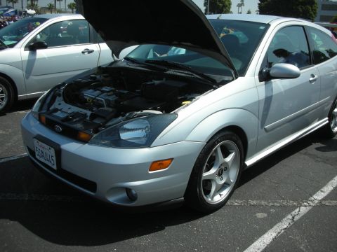 2004 Ford Crown Victoria - Silver Ford Focus coupe with hood open, parked next to another car at an outdoor event.