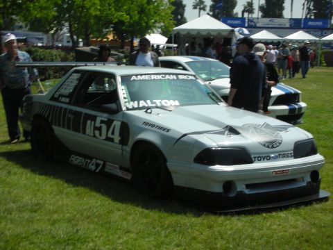 2004 Ford Crown Victoria - A modified race car with sponsor decals sits on grass at an outdoor event.