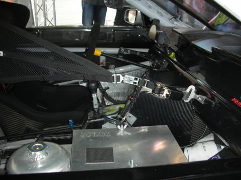 2004 Ford Crown Victoria - The interior of a race car features a racing seat, shifter, and safety harness, with a 'TAYLOR' branded box visible.