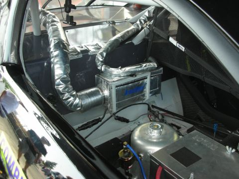 2004 Ford Crown Victoria - The interior of a race car shows custom modifications including silver insulated ducting and a cooling unit.