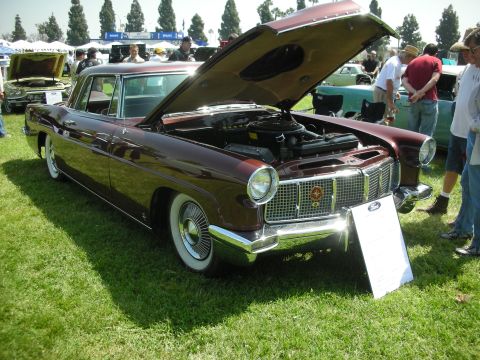 2004 Ford Crown Victoria - A maroon 1956 Continental is displayed with its hood open, revealing the engine, at a car show with other vehicles present.