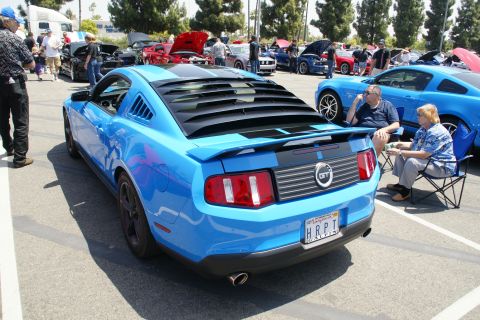 1992 Ford Taurus - A blue Ford Mustang GT is parked at a car show, distinctive rear louvers and racing stripes.