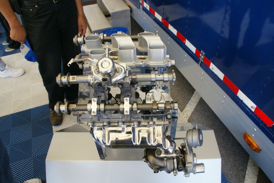 Engine with turbocharger on display stand next to a blue truck