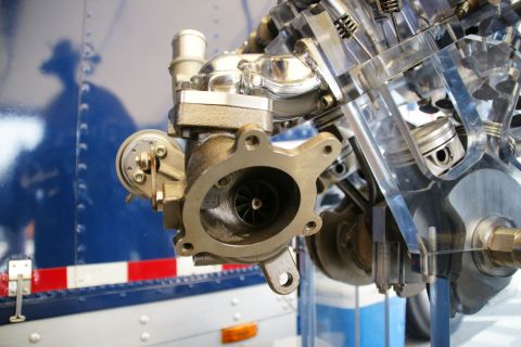 1992 Ford Taurus - A close-up view of a turbocharger attached to a cutaway engine, revealing internal components like pistons and the crankshaft.