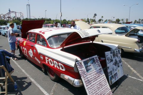 1992 Ford Taurus - A 1957 Ford Custom Fairlane is displayed with its hood and trunk open at an outdoor car show.