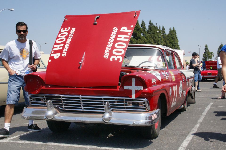 Red and white 1957 Ford Fairlane 500 Skyliner with hood open, showing "SUPERCHARGED 300 H.P." text