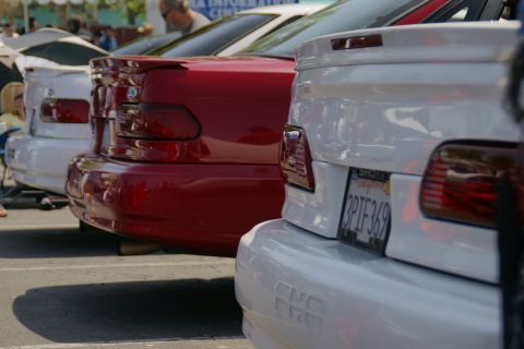 1992 Ford Taurus - Rear view of multiple sedans parked in a lot, one is red and two are white.