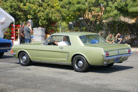1992 Ford Taurus - A light green 1965 Ford Mustang coupe is seen from the rear 3/4 angle, parked next to another vehicle.