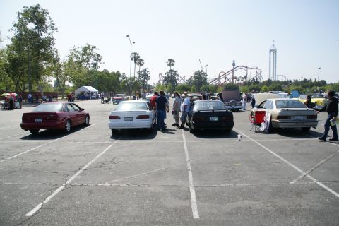 1992 Ford Taurus - A gathering of vehicles in a parking lot with a theme park visible in the distance.