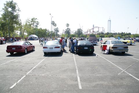 1992 Ford Taurus - Several cars are parked in an outdoor lot with a roller coaster in the background.