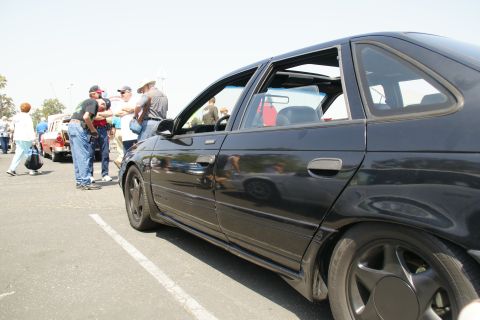1992 Ford Taurus - A black 1992 Ford Taurus is parked at an outdoor event, with several people gathered nearby.