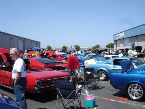 1978 Ford Mustang II - A car show features numerous classic vehicles, including a red convertible and several blue coupes.
