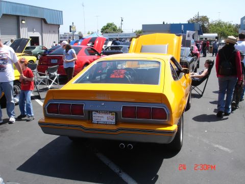 1978 Ford Mustang II - A yellow 1974 Ford Mustang II is displayed at a car show with its hood open.