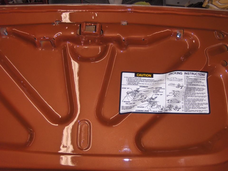 Underhood caution and jacking instructions label with spare tire stowage diagram on painted hood
